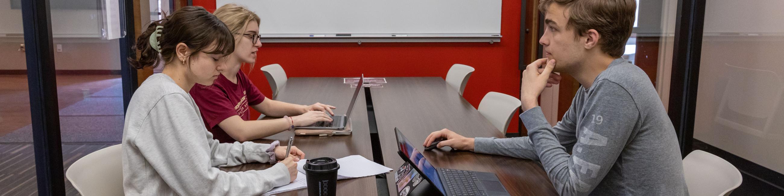 One male and two females working together in a study room.