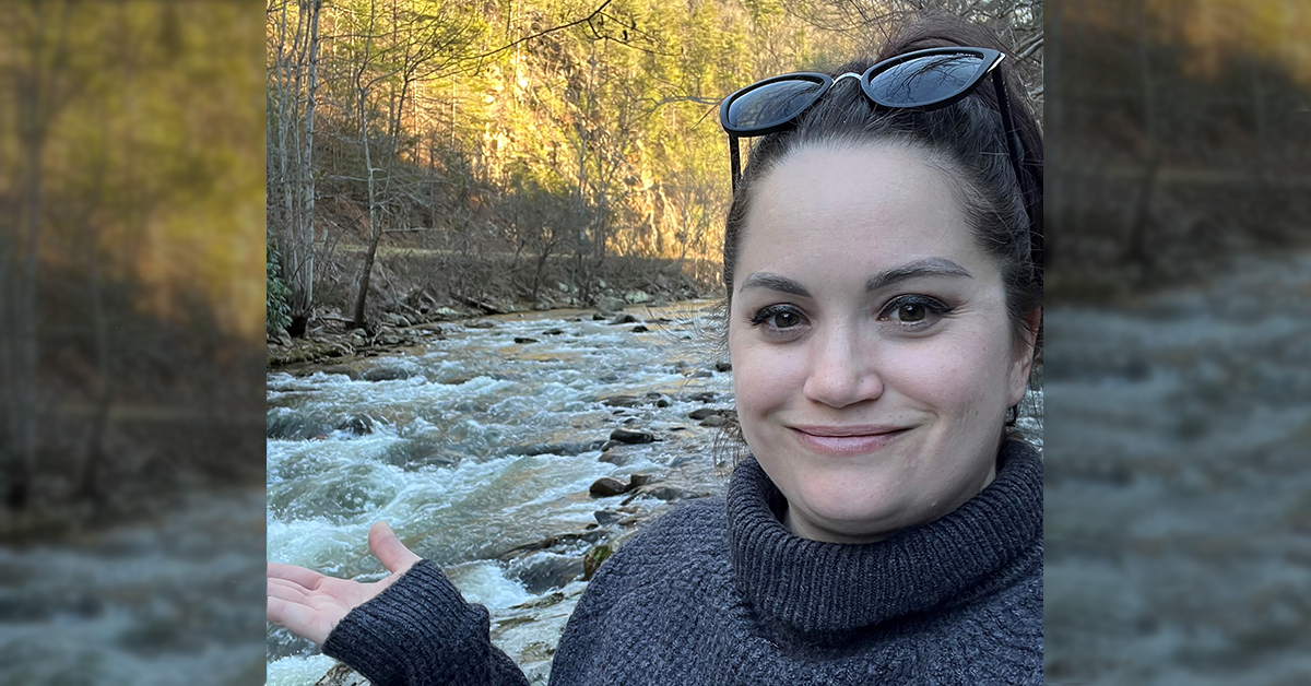 Photo of Kristina McDowell hiking by river in fall