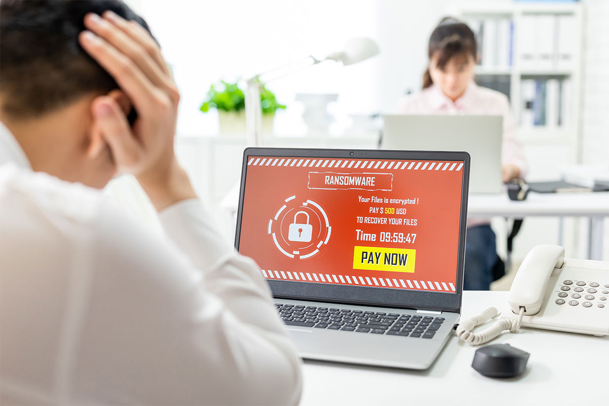 A man on his laptop receiving a ransomware message. 