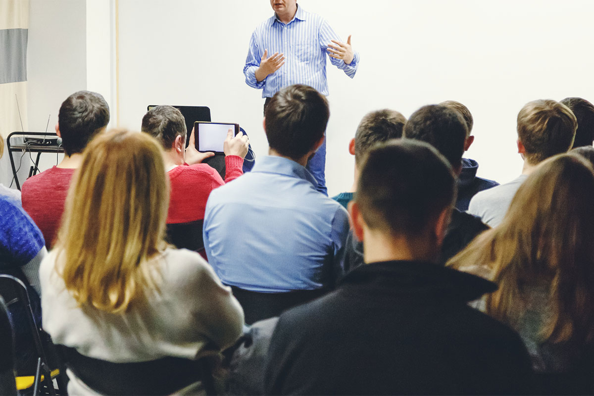 A professor lecturing to students at the front of the classroom.