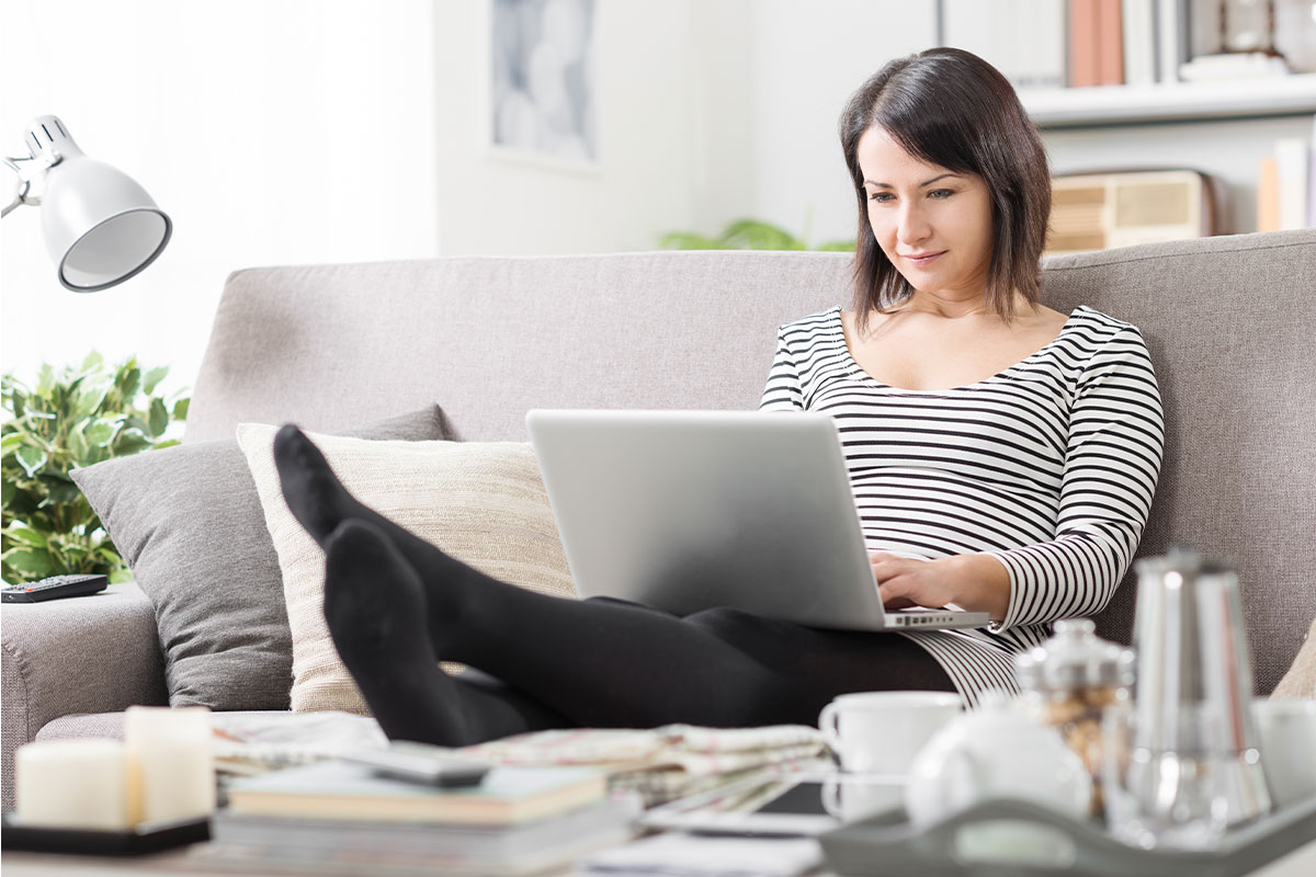 Female sitting on her couch on her laptop.