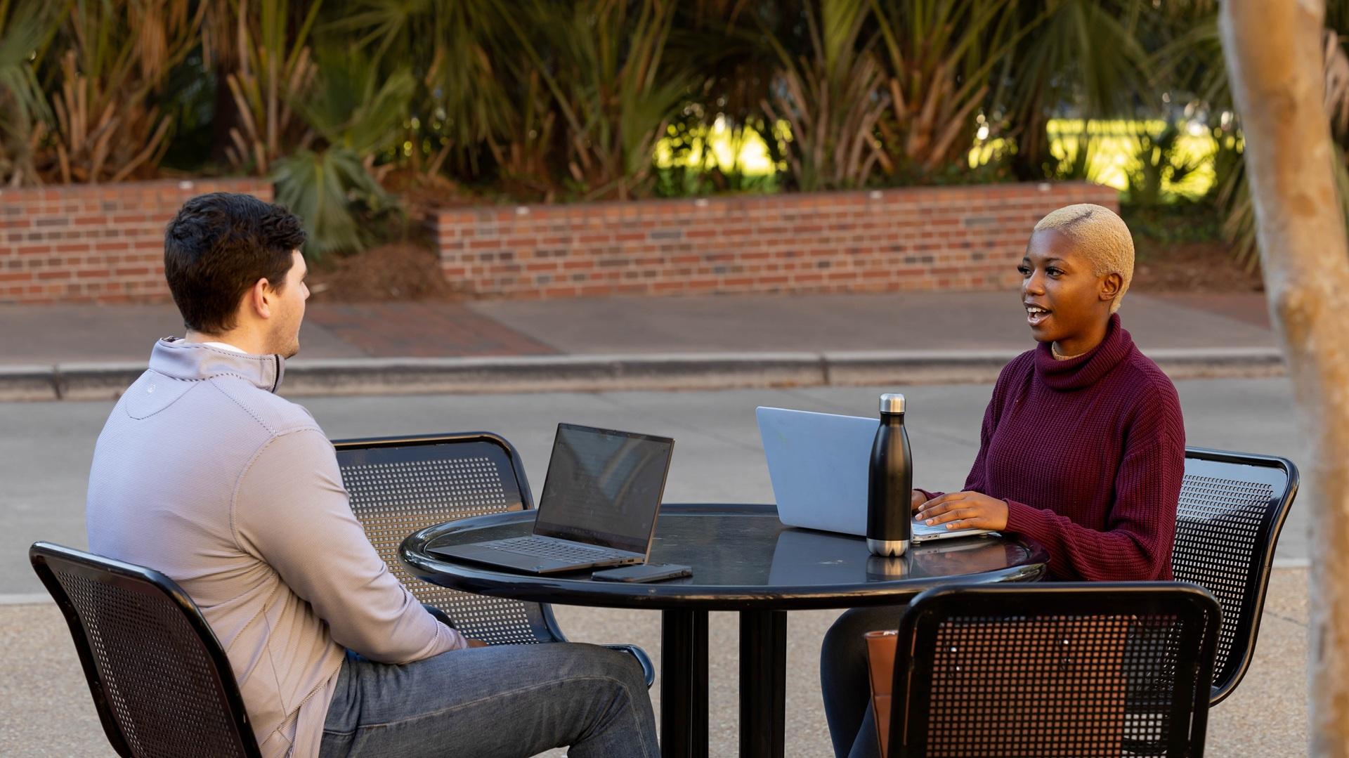 Students sitting at table with laptops